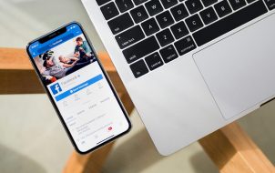 Facebook App Open in iPhone Next to a MacBook